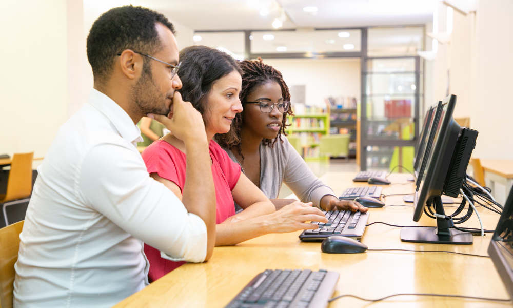 Three adult delegates working together in a classroom representing in-person training.